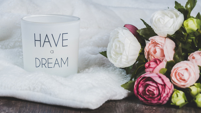 A picture of a bouquet of flowers next to a white cup with the words "have a dream".